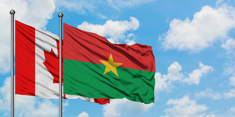 Canada and Burkina Faso flag waving in the wind against white cloudy blue sky together. Diplomacy concept, international relations.