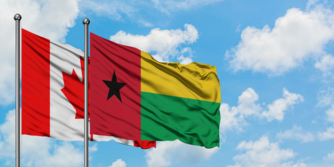 Canada and Guinea Bissau flag waving in the wind against white cloudy blue sky together. Diplomacy concept, international relations.
