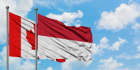 Canada and Indonesia flag waving in the wind against white cloudy blue sky together. Diplomacy concept, international relations.