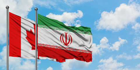 Canada and Iran flag waving in the wind against white cloudy blue sky together. Diplomacy concept, international relations.