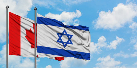 Canada and Israel flag waving in the wind against white cloudy blue sky together. Diplomacy concept, international relations.