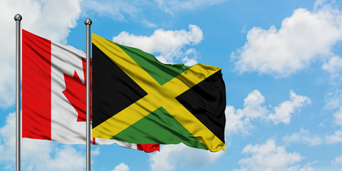 Canada and Jamaica flag waving in the wind against white cloudy blue sky together. Diplomacy concept, international relations.
