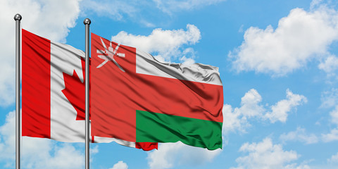 Canada and Oman flag waving in the wind against white cloudy blue sky together. Diplomacy concept, international relations.