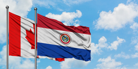 Canada and Paraguay flag waving in the wind against white cloudy blue sky together. Diplomacy concept, international relations.
