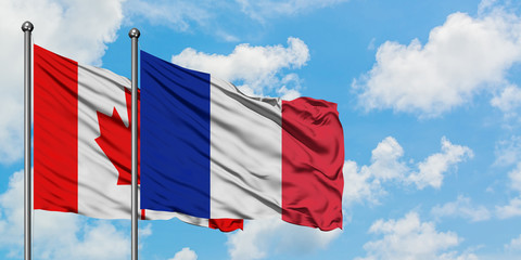 Canada and Reunion flag waving in the wind against white cloudy blue sky together. Diplomacy concept, international relations.