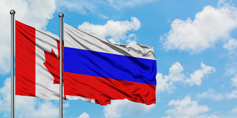 Canada and Russia flag waving in the wind against white cloudy blue sky together. Diplomacy concept, international relations.
