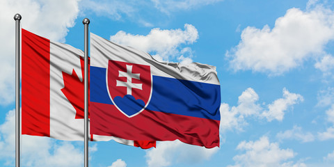 Canada and Slovakia flag waving in the wind against white cloudy blue sky together. Diplomacy concept, international relations.