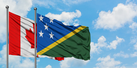 Canada and Solomon Islands flag waving in the wind against white cloudy blue sky together. Diplomacy concept, international relations.