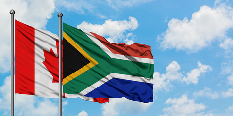 Canada and South Africa flag waving in the wind against white cloudy blue sky together. Diplomacy concept, international relations.