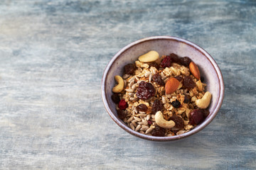 Bowl of granola with nuts and raisins. Concept for a tasty and healthy meal. Rustic wooden background. Copy space. 