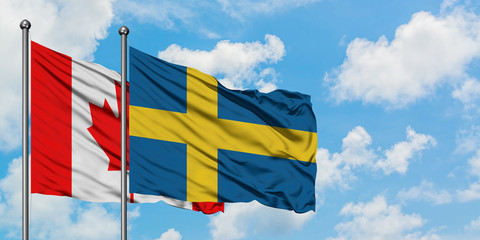 Canada and Sweden flag waving in the wind against white cloudy blue sky together. Diplomacy concept, international relations.