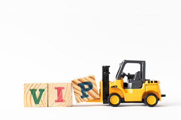 Toy forklift hold wood letter block P to complete word VIP (Abbreviation of very important person)...
