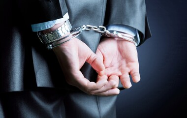 Cropped image of male hands in handcuffs behind his back