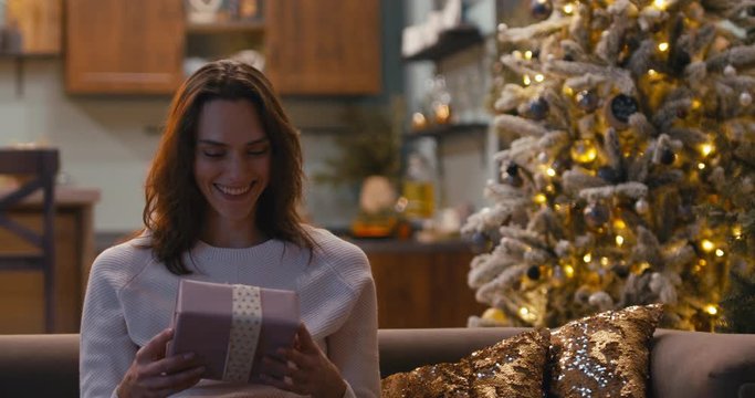 Caucasian couple or family celebrating Christmas at home, exchanging presents, smiling and lauging. 4K UHD RAW graded footage