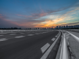 Asphalt road and the beautiful urban skyline at sunset