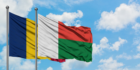 Chad and Madagascar flag waving in the wind against white cloudy blue sky together. Diplomacy concept, international relations.