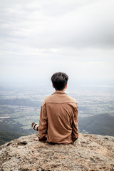 Fototapeta premium Trekker sitting on the mountain with Beautiful Sunrise and sea of mist in the morning on Khao Luang mountain in Ramkhamhaeng National Park,Sukhothai province Thailand