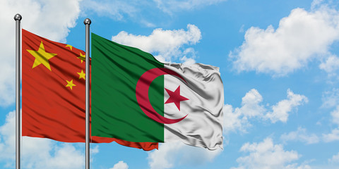 China and Algeria flag waving in the wind against white cloudy blue sky together. Diplomacy concept, international relations.
