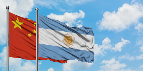 China and Argentina flag waving in the wind against white cloudy blue sky together. Diplomacy concept, international relations.