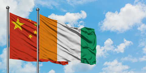China and Cote D'Ivoire flag waving in the wind against white cloudy blue sky together. Diplomacy concept, international relations.