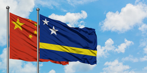 China and Curacao flag waving in the wind against white cloudy blue sky together. Diplomacy concept, international relations.