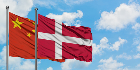 China and Denmark flag waving in the wind against white cloudy blue sky together. Diplomacy concept, international relations.