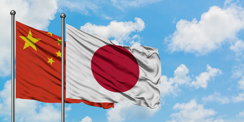 China and Japan flag waving in the wind against white cloudy blue sky together. Diplomacy concept, international relations.