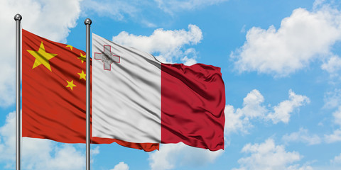 China and Malta flag waving in the wind against white cloudy blue sky together. Diplomacy concept, international relations.
