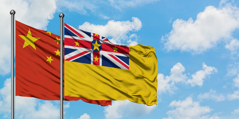 China and Niue flag waving in the wind against white cloudy blue sky together. Diplomacy concept, international relations.