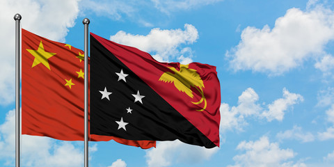China and Papua New Guinea flag waving in the wind against white cloudy blue sky together. Diplomacy concept, international relations.