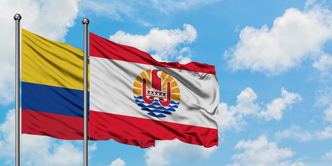 Colombia and French Polynesia flag waving in the wind against white cloudy blue sky together. Diplomacy concept, international relations.