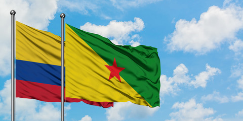 Colombia and French Guiana flag waving in the wind against white cloudy blue sky together. Diplomacy concept, international relations.