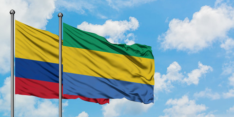 Colombia and Gabon flag waving in the wind against white cloudy blue sky together. Diplomacy...