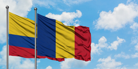 Colombia and Romania flag waving in the wind against white cloudy blue sky together. Diplomacy...