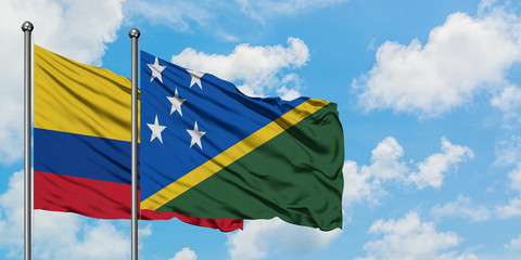 Colombia and Solomon Islands flag waving in the wind against white cloudy blue sky together. Diplomacy concept, international relations.