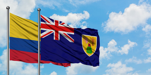 Colombia and Turks And Caicos Islands flag waving in the wind against white cloudy blue sky together. Diplomacy concept, international relations.