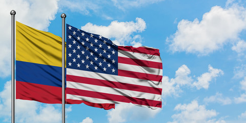 Colombia and United States flag waving in the wind against white cloudy blue sky together. Diplomacy concept, international relations.