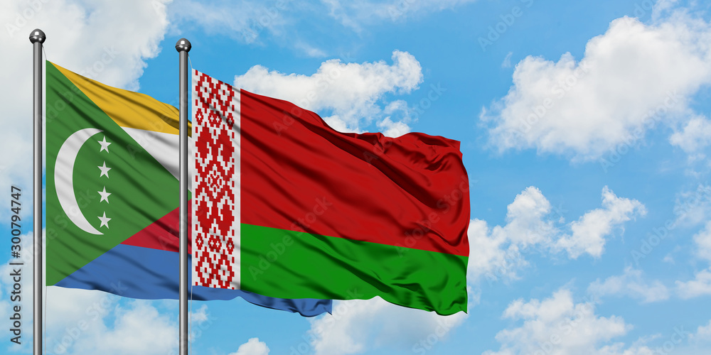 Wall mural Comoros and Belarus flag waving in the wind against white cloudy blue sky together. Diplomacy concept, international relations.