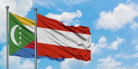 Comoros and Austria flag waving in the wind against white cloudy blue sky together. Diplomacy concept, international relations.