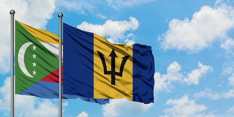 Comoros and Barbados flag waving in the wind against white cloudy blue sky together. Diplomacy concept, international relations.