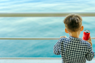 Fototapeta premium Asian boy stands on baluster of ferry for relaxing and look at the ocean and island