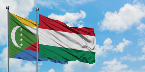 Comoros and Hungary flag waving in the wind against white cloudy blue sky together. Diplomacy concept, international relations.