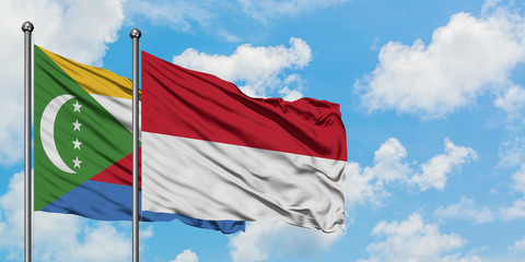 Comoros and Indonesia flag waving in the wind against white cloudy blue sky together. Diplomacy concept, international relations.