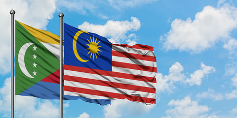 Comoros and Malaysia flag waving in the wind against white cloudy blue sky together. Diplomacy concept, international relations.