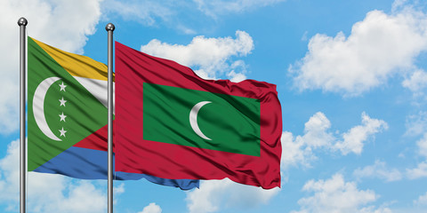 Comoros and Maldives flag waving in the wind against white cloudy blue sky together. Diplomacy concept, international relations.