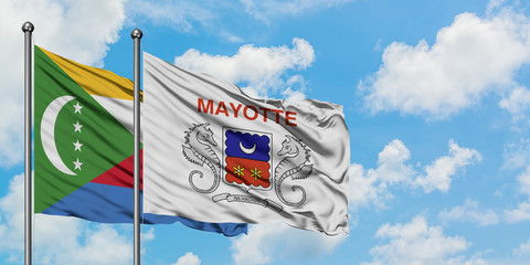 Comoros and Mayotte flag waving in the wind against white cloudy blue sky together. Diplomacy...