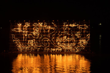 Traditional fire boat floating in Mekong river at night in Nakhon Phanom, Thailand