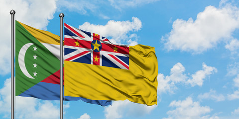 Comoros and Niue flag waving in the wind against white cloudy blue sky together. Diplomacy concept, international relations.