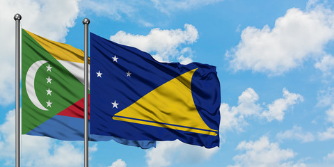 Comoros and Tokelau flag waving in the wind against white cloudy blue sky together. Diplomacy concept, international relations.