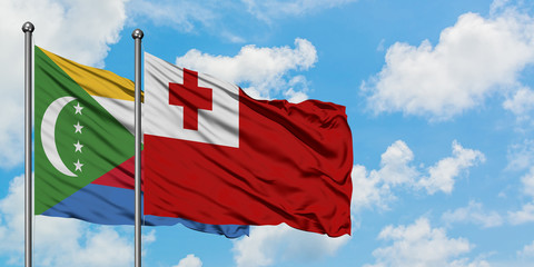 Comoros and Tonga flag waving in the wind against white cloudy blue sky together. Diplomacy concept, international relations.